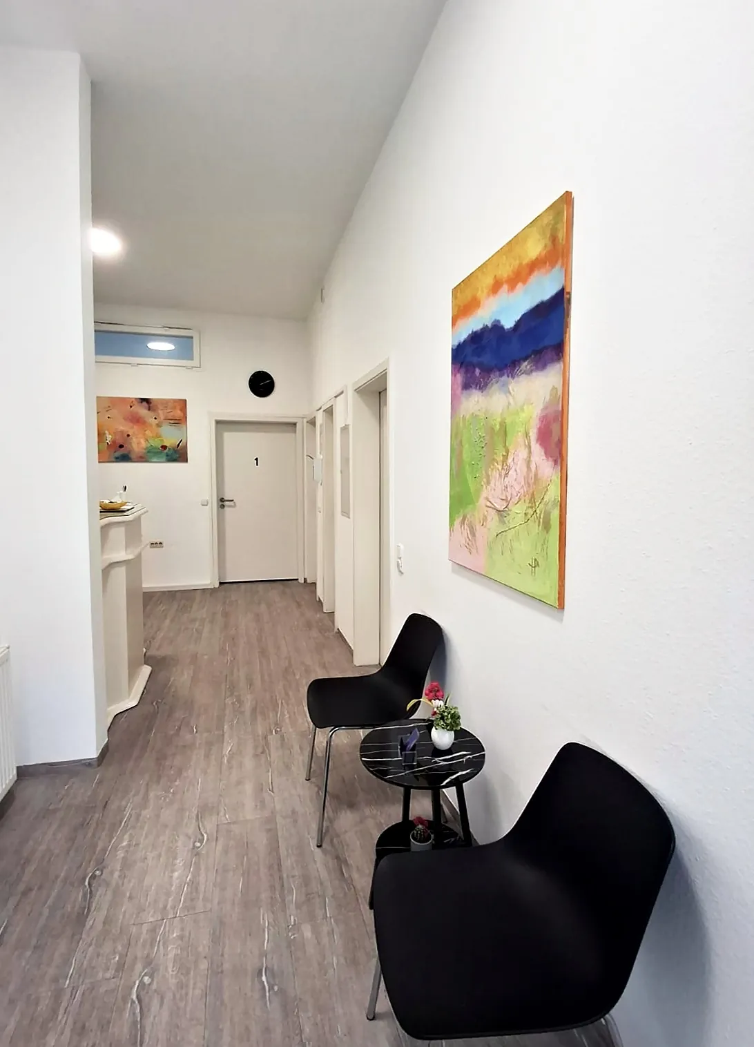 Heller Flur der Praxis mit Wartebereich und farbigem Bild